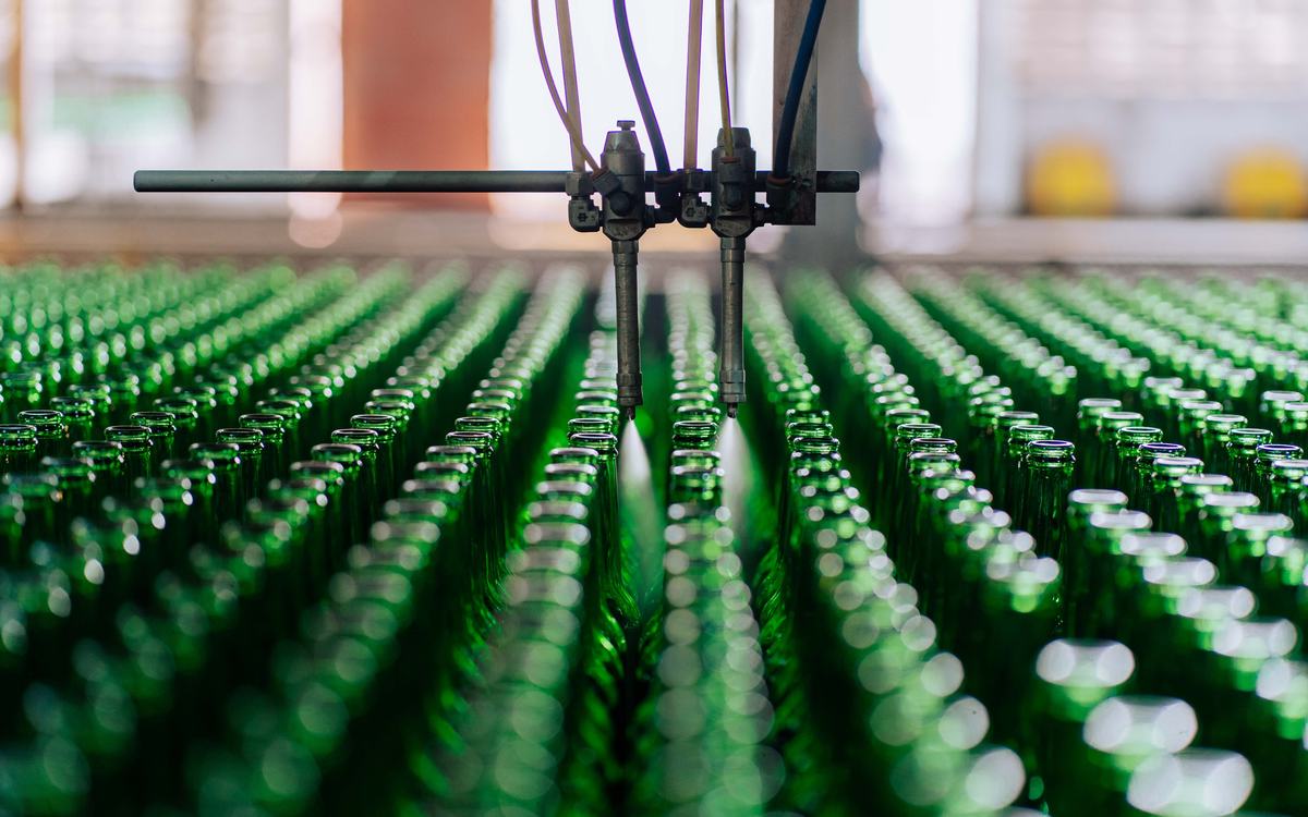 Ligne automatisée pulvérisant des rangées de bouteilles en verre vert