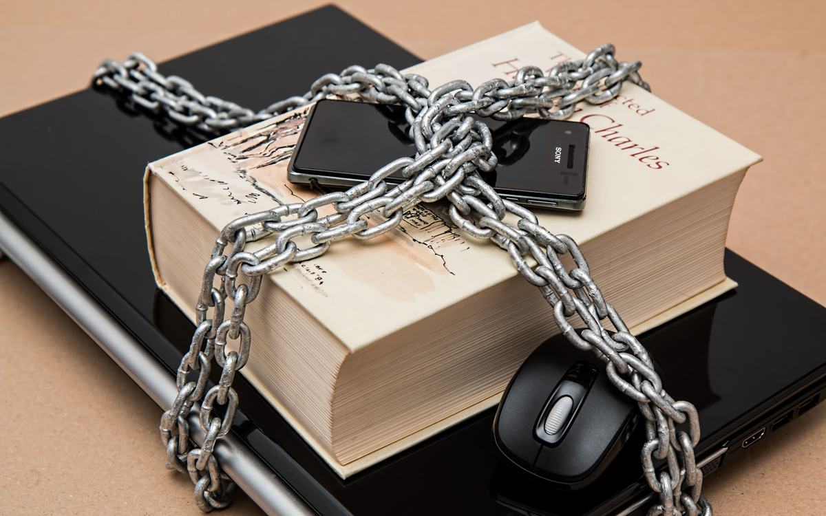 Ordinateur portable, téléphone et livre verrouillés par une chaîne