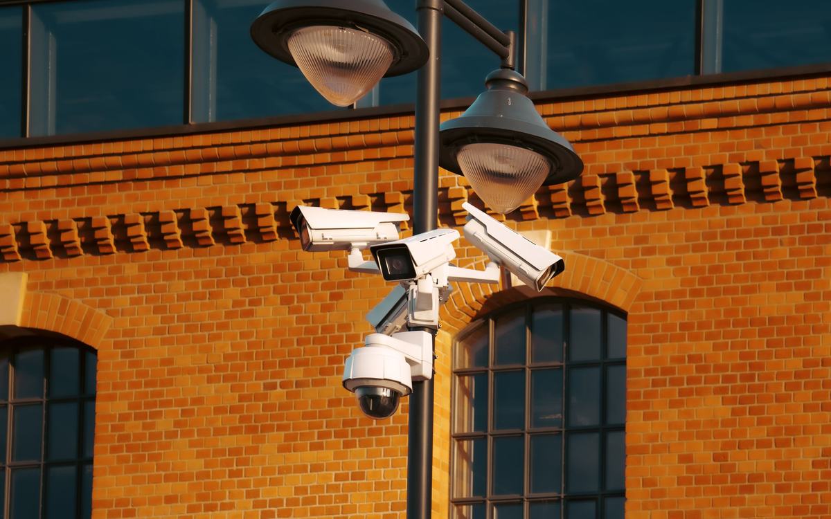 Caméras de vidéosurveillance sur un poteau devant un bâtiment en briques